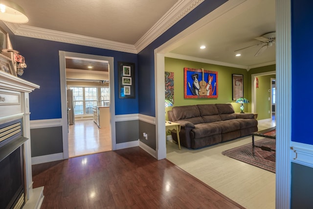 entryway featuring baseboards, a ceiling fan, ornamental molding, wood finished floors, and a fireplace