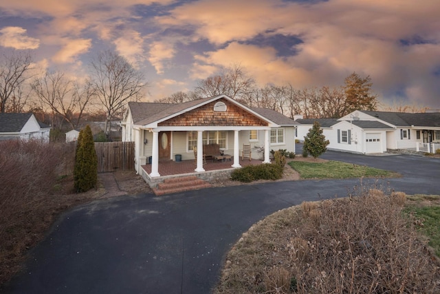 bungalow-style house featuring driveway, a garage, a residential view, fence, and a porch