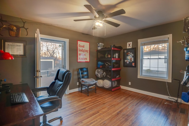 office area with a healthy amount of sunlight, ceiling fan, baseboards, and wood finished floors