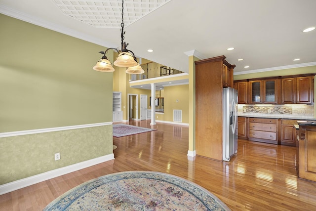 kitchen with ornamental molding, pendant lighting, hardwood / wood-style floors, and stainless steel fridge with ice dispenser