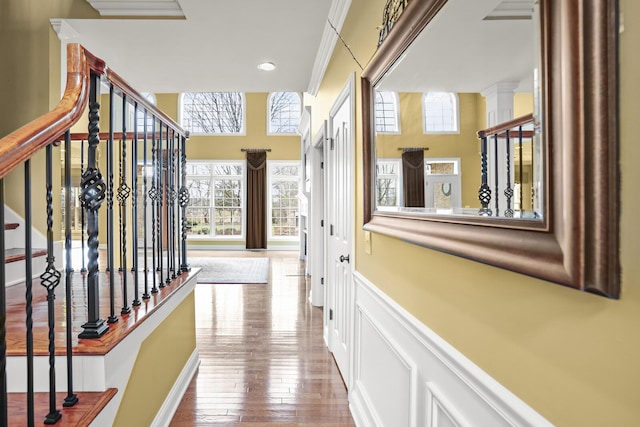 hall with hardwood / wood-style flooring, crown molding, a wealth of natural light, and ornate columns