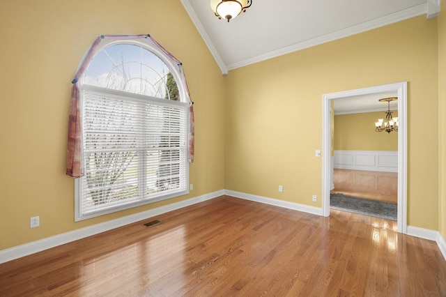 unfurnished room with crown molding, a chandelier, vaulted ceiling, and hardwood / wood-style flooring