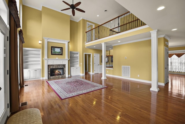 unfurnished living room featuring ornate columns, crown molding, wood-type flooring, and ceiling fan