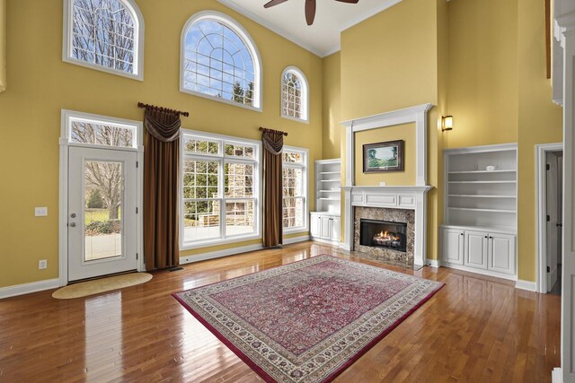 living room with hardwood / wood-style floors, a fireplace, ornamental molding, and a high ceiling