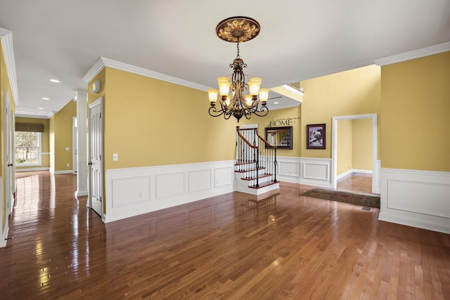 empty room with crown molding, dark wood-type flooring, and a chandelier