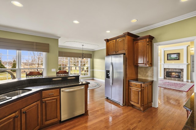 kitchen with sink, crown molding, wood-type flooring, appliances with stainless steel finishes, and pendant lighting