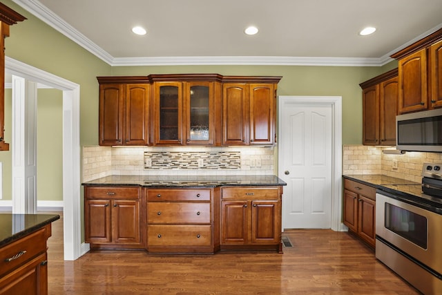 kitchen with stainless steel appliances, ornamental molding, dark wood-type flooring, and backsplash