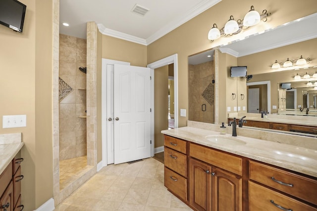 bathroom featuring vanity, tile patterned flooring, ornamental molding, and tiled shower