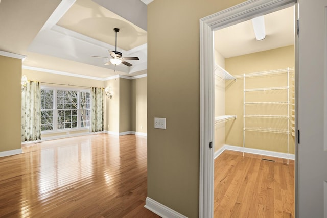 interior space with ceiling fan, a tray ceiling, and light hardwood / wood-style floors