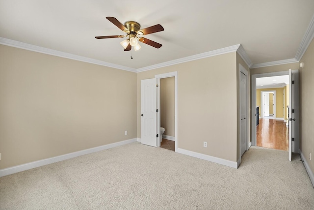 unfurnished bedroom featuring crown molding, light colored carpet, ceiling fan, and ensuite bath