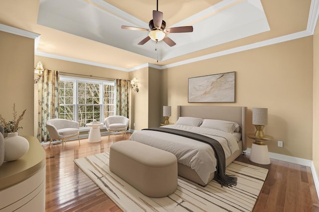 bedroom featuring a raised ceiling, ornamental molding, and hardwood / wood-style flooring