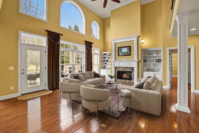 living room featuring hardwood / wood-style floors, ornamental molding, a premium fireplace, and ceiling fan