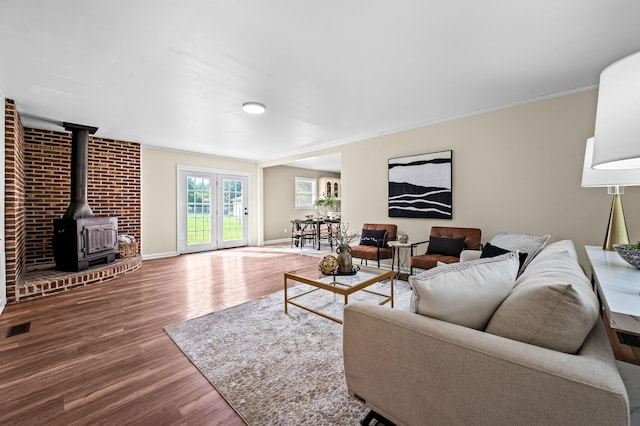 living room with hardwood / wood-style floors, crown molding, french doors, and a wood stove