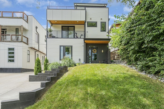 back of property with a balcony and a lawn