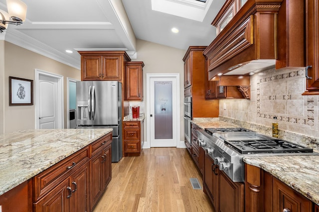 kitchen featuring decorative backsplash, custom exhaust hood, light stone counters, light hardwood / wood-style floors, and stainless steel appliances