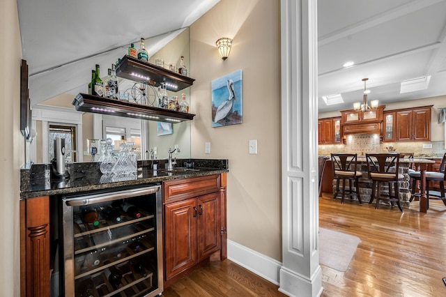 bar with sink, dark stone countertops, wine cooler, wood-type flooring, and decorative backsplash