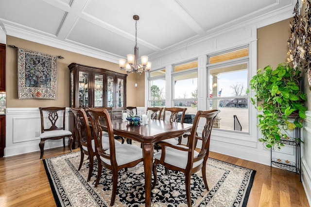 dining space featuring light hardwood / wood-style flooring, an inviting chandelier, beam ceiling, coffered ceiling, and ornamental molding