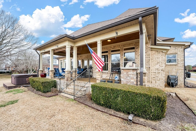 rear view of property featuring a hot tub and covered porch