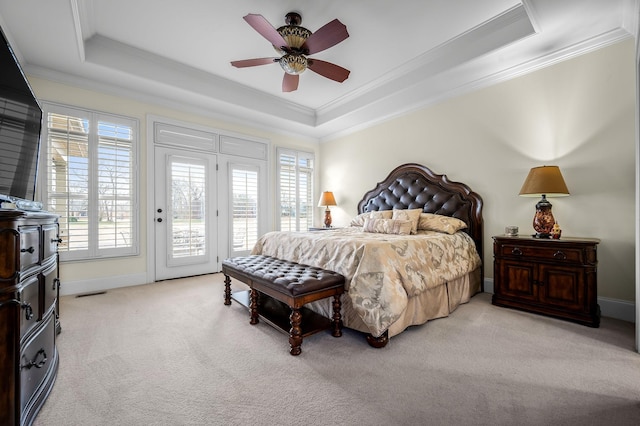 carpeted bedroom featuring multiple windows, access to exterior, and a tray ceiling