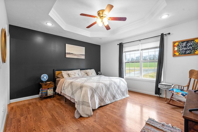 bedroom with a raised ceiling, ornamental molding, hardwood / wood-style floors, and ceiling fan