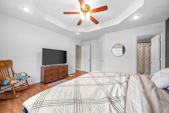 bedroom featuring a raised ceiling, ornamental molding, ceiling fan, and light hardwood / wood-style flooring