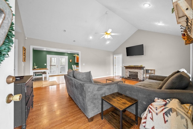 living room with high vaulted ceiling, a fireplace, ceiling fan, light hardwood / wood-style floors, and french doors