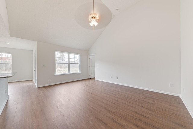 unfurnished living room with ceiling fan, high vaulted ceiling, and dark hardwood / wood-style flooring