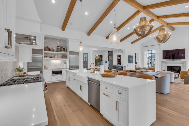 kitchen with a spacious island, sink, white cabinetry, decorative light fixtures, and stainless steel appliances