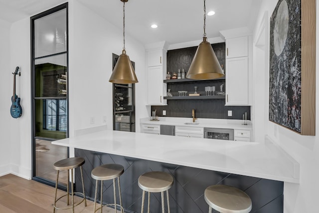 kitchen featuring pendant lighting, a breakfast bar area, white cabinets, and kitchen peninsula