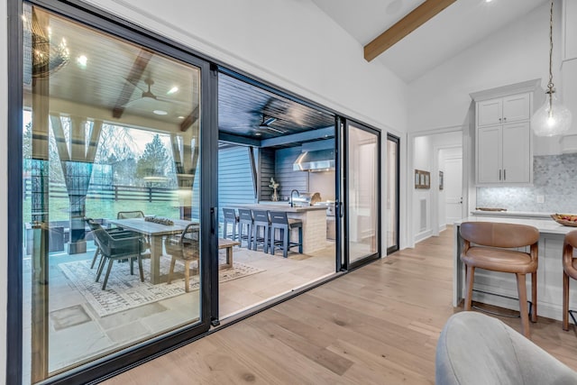 interior space featuring high vaulted ceiling, sink, ceiling fan, light hardwood / wood-style floors, and beam ceiling