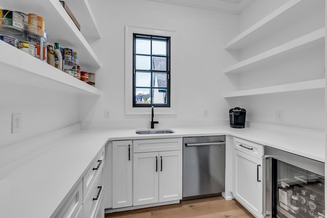 kitchen with white cabinetry, stainless steel dishwasher, beverage cooler, and sink