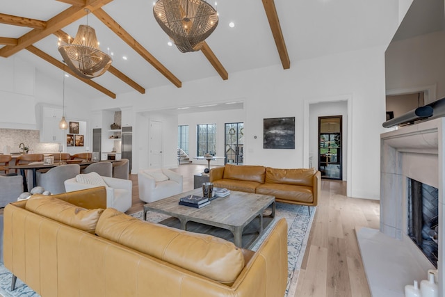 living room with an inviting chandelier, high vaulted ceiling, light hardwood / wood-style floors, and beamed ceiling