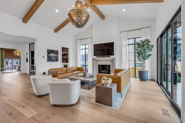 living room featuring an inviting chandelier, light hardwood / wood-style flooring, and beamed ceiling