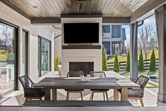 sunroom / solarium featuring an outdoor brick fireplace and wood ceiling