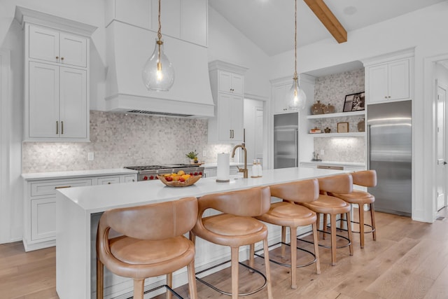 kitchen with a kitchen island with sink, stainless steel built in fridge, and a kitchen bar