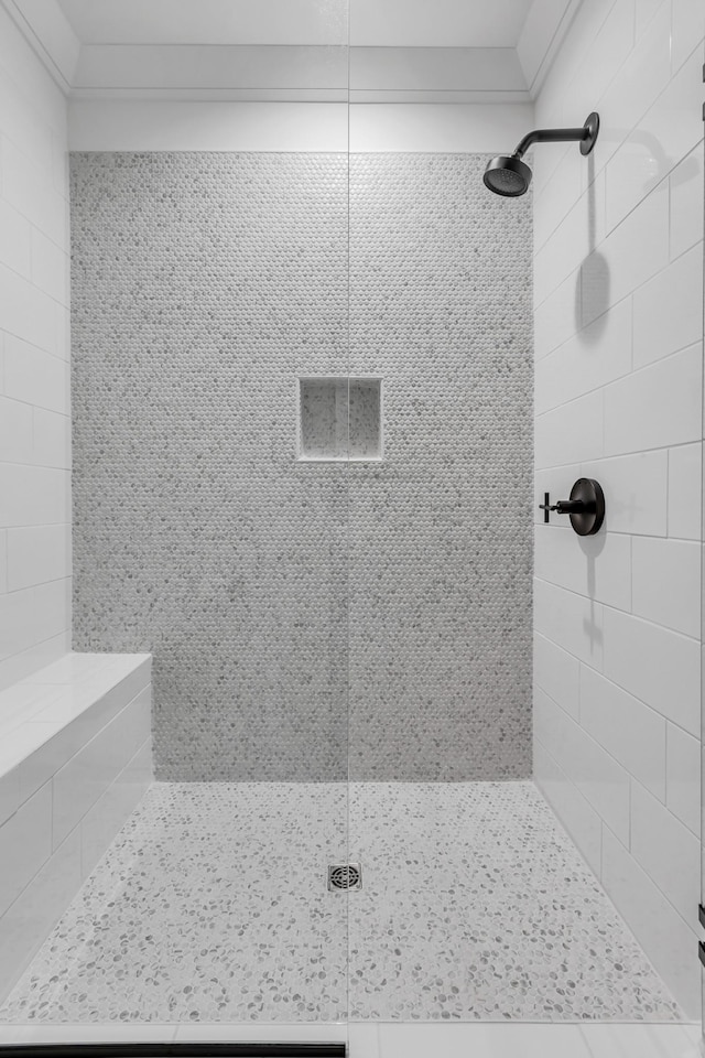 bathroom with a tile shower and ornamental molding