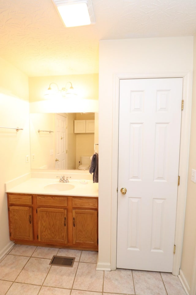 bathroom featuring vanity, tile patterned flooring, and toilet