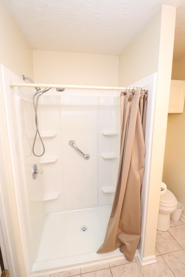 bathroom featuring tile patterned flooring, toilet, a textured ceiling, and a shower with shower curtain