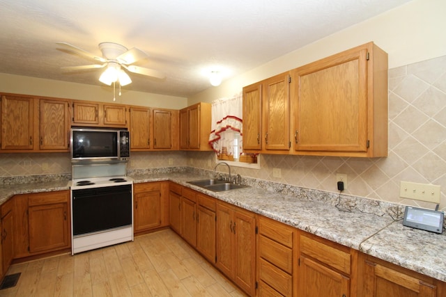 kitchen featuring sink, electric range, ceiling fan, light stone counters, and light hardwood / wood-style flooring