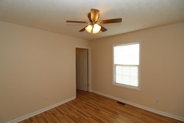 unfurnished room with ceiling fan, a textured ceiling, and light wood-type flooring