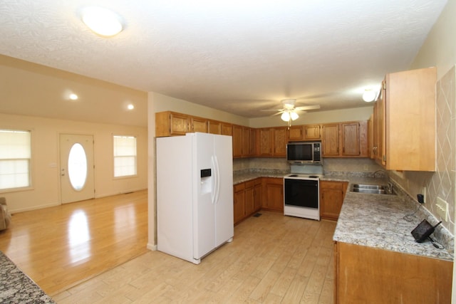 kitchen featuring sink, decorative backsplash, white appliances, and light hardwood / wood-style flooring