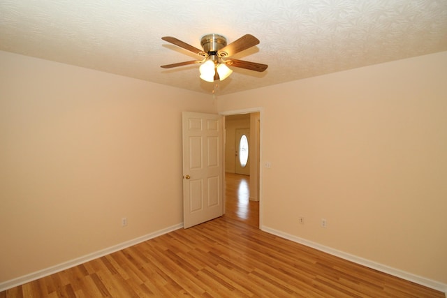 empty room with ceiling fan, a textured ceiling, and light hardwood / wood-style floors