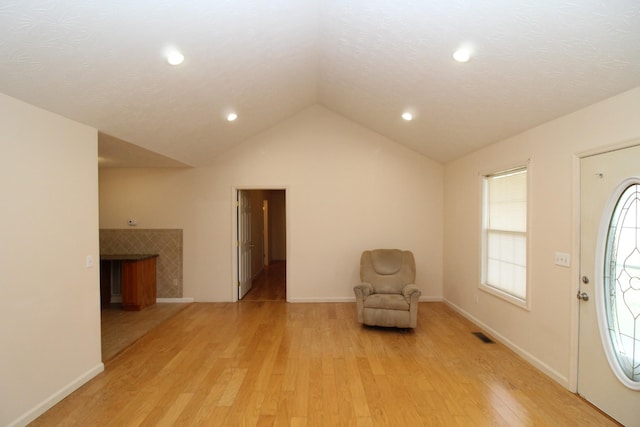 unfurnished room featuring lofted ceiling, light hardwood / wood-style flooring, and a tile fireplace