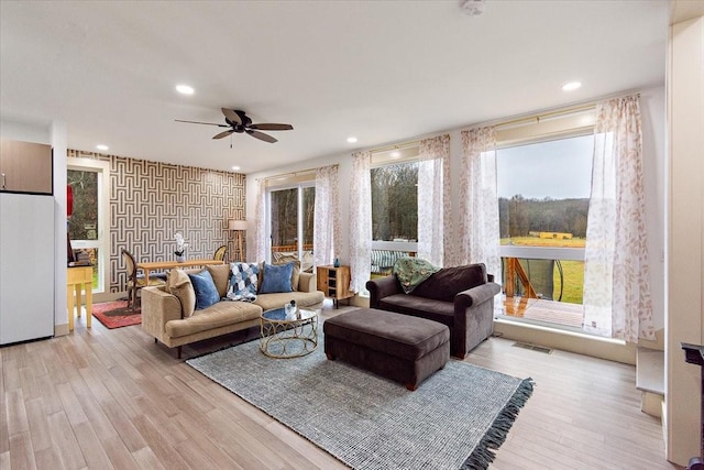 living area featuring a ceiling fan, recessed lighting, visible vents, and light wood-style flooring