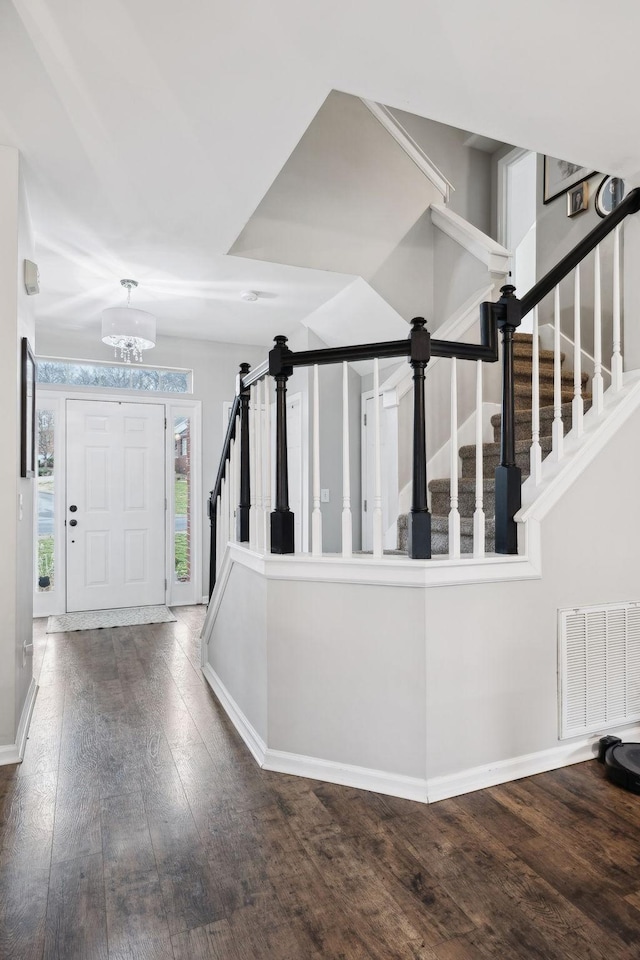 stairs with wood-type flooring and a notable chandelier