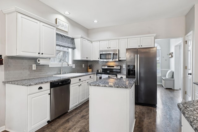 kitchen featuring a kitchen island, sink, white cabinets, dark stone counters, and stainless steel appliances