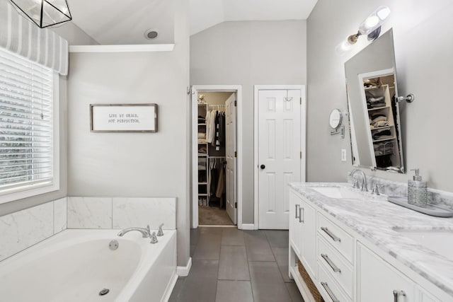 bathroom featuring lofted ceiling, vanity, a bathing tub, and tile patterned flooring