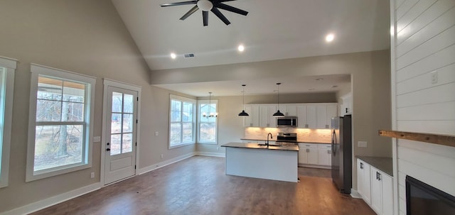 kitchen with sink, hanging light fixtures, a center island with sink, fridge, and white cabinets