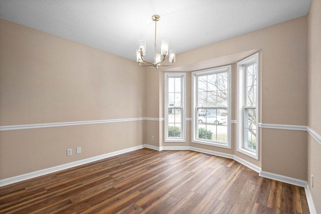 unfurnished room featuring dark wood-type flooring and a chandelier