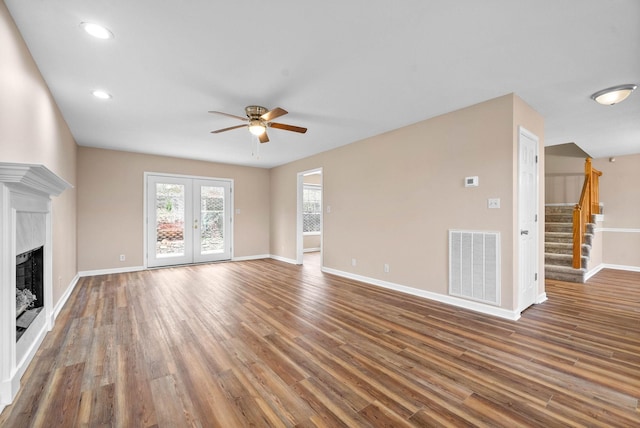 unfurnished living room featuring dark wood-type flooring, ceiling fan, a premium fireplace, and french doors